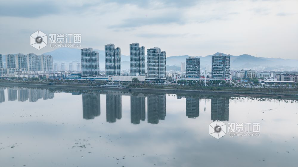2026年3月30日,江西省吉安市吉水县清晨下完雨后,水面平静得像一面镜子,岸边的建筑倒映在水中与空中的云雾形成一幅江南画卷。
