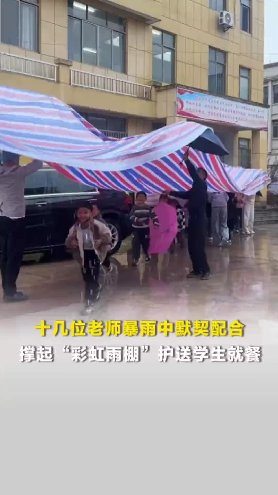 十几位老师暴雨中默契配合，撑起“彩虹雨伞”护送学生就餐