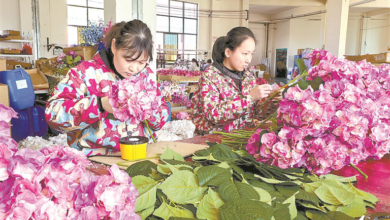 位于万载工业园的江西依美鸿工艺品有限公司生产车间内,工人在加工出口欧洲的仿真绣球花。