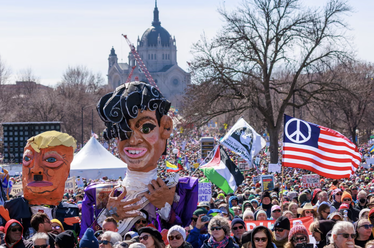 在美国明尼苏达州圣保罗,民众聚集时举着美国总统特朗普和已故美国歌手普林斯的模拟人像。