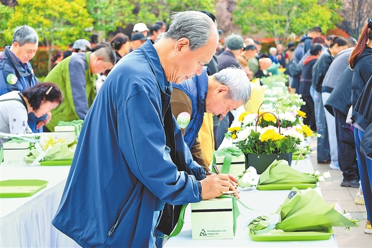 在河南福寿园举行的郑州市2026年清明节公益树葬活动中，家属们在树木年轮祈福牌上写下祝福的话语。 受访者供图