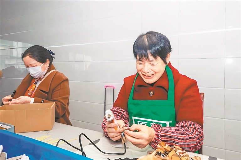 张佑辉(右)在给发卡打胶。 通讯员 姚雨婷摄