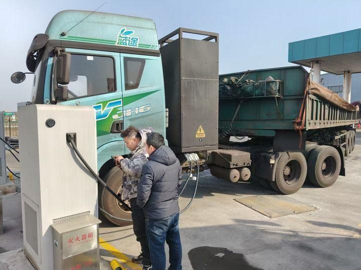 ↑司机张杰（左）操作手机App给重卡充电。