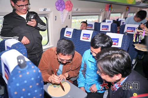“春游”列车上,旅客参与绘制团扇活动。