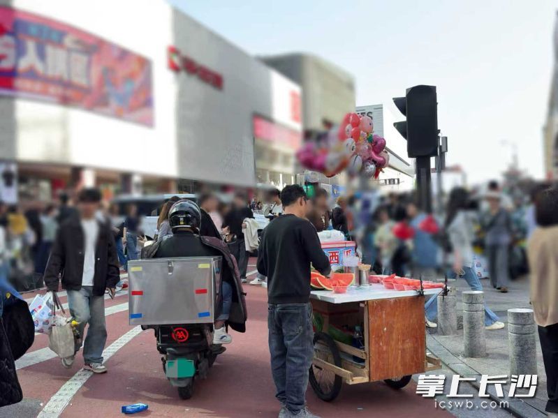 人行道旁变摊位,行人绕路难行。