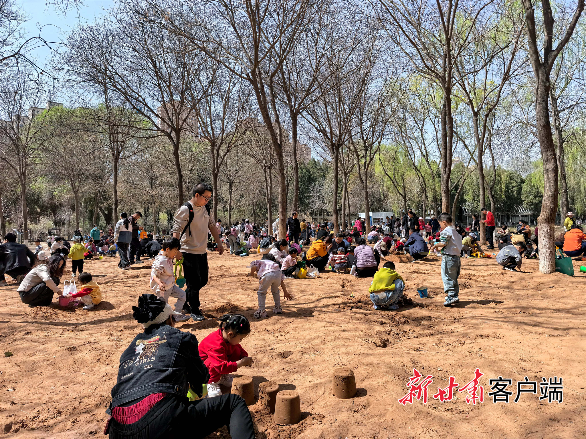 家长携带孩子在沙滩上做手工