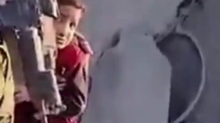 以军士兵在镜头前假装与巴勒斯坦儿童互动，身旁儿童光着脚丫止不住颤抖