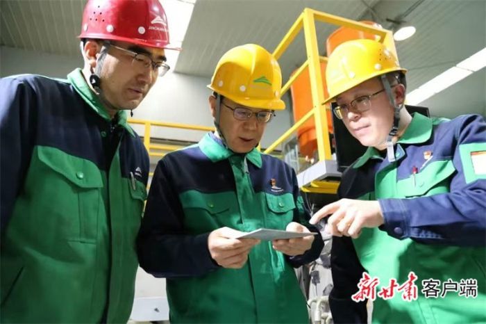 胡家彦（中）在电子束熔炼炉前与技术人员现场交流