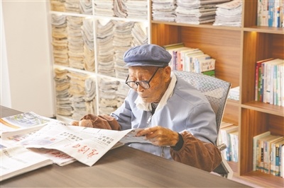 姜云鹤老人专注阅读当日报纸，神情沉静而投入。黄苏明摄