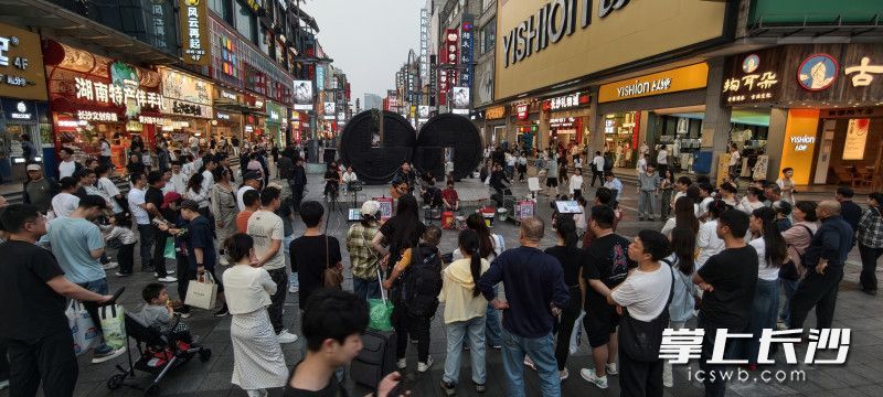 街头艺人的表演吸引南来北往的行人驻足观赏。