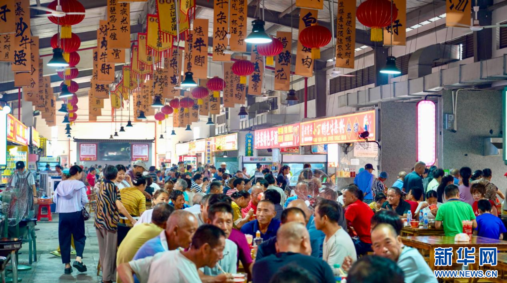 在南昌县三江镇早酒集市，食客们围坐桌前品尝特色美食。新华网发