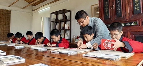 青田书院院长洪志文指导小朋友体验雕版技艺。通讯员 邱政寅摄