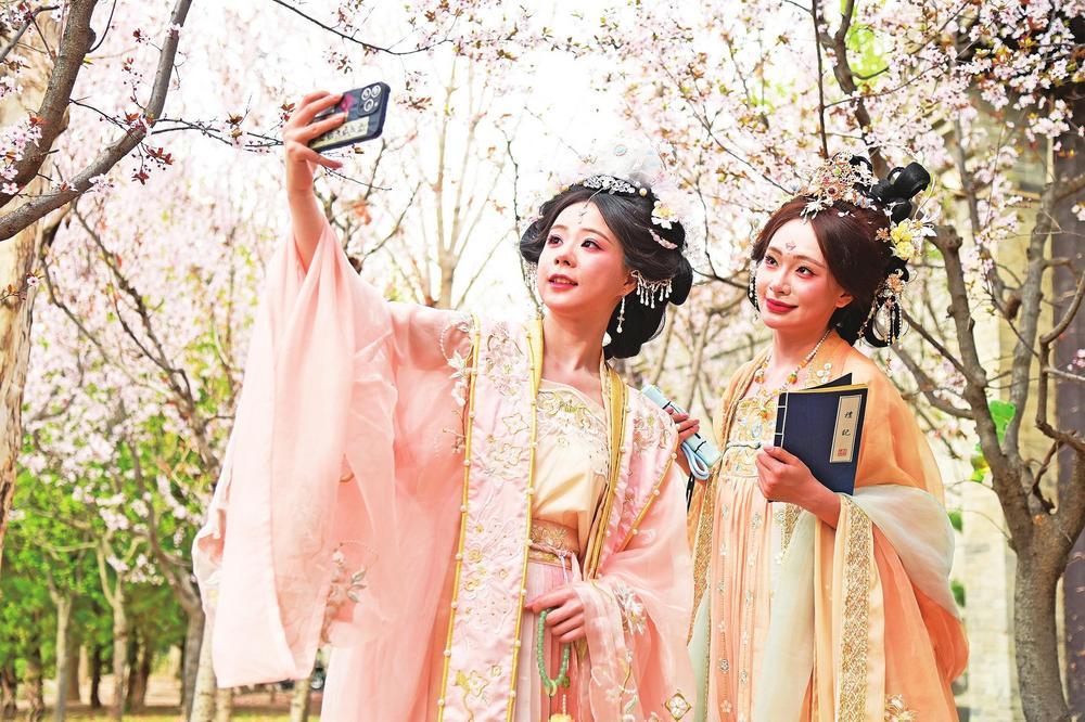 随着天气回暖，很多年轻人穿着汉服赏花春游，成为又一道春日新景。