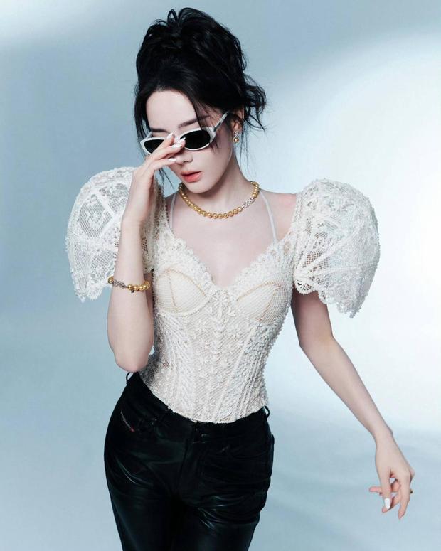 迪丽热巴手轻扶墨镜，珍珠项链与蕾丝衫呼应，，尽显摩登女郎风范。
