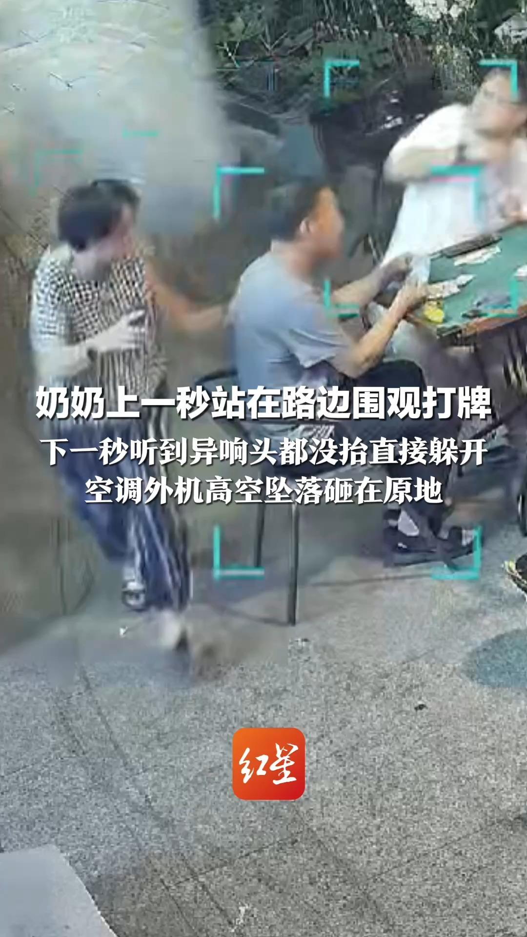 神级反应！多停留1秒就被砸到 奶奶上一秒站在路边围观打牌 下一秒听到异响头都没抬直接躲开 空调外机高空坠落砸在原地