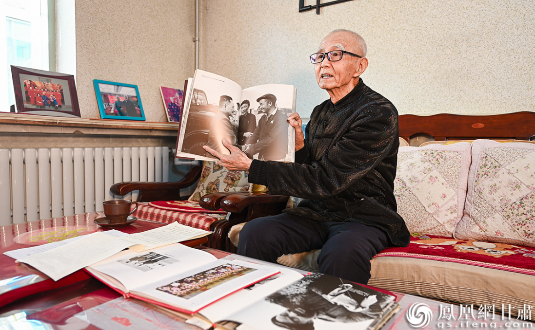 邱岳泰翻开珍藏图册,讲述铁人故事。杨艺锴 摄
