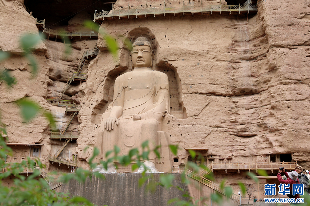 游客在炳灵寺石窟前拍照打卡　新华网发　王生元　摄