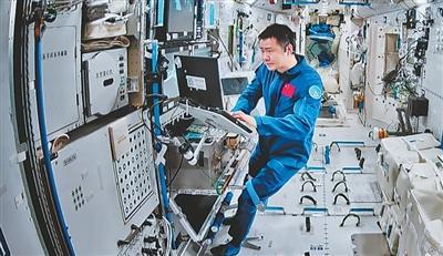 在北京航天飞行控制中心屏幕上拍摄的陈冬在空间站组合体舱内工作画面。