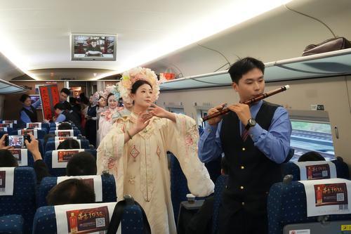 列车乘务员为旅客展示书法、汉服秀和竹笛演奏。