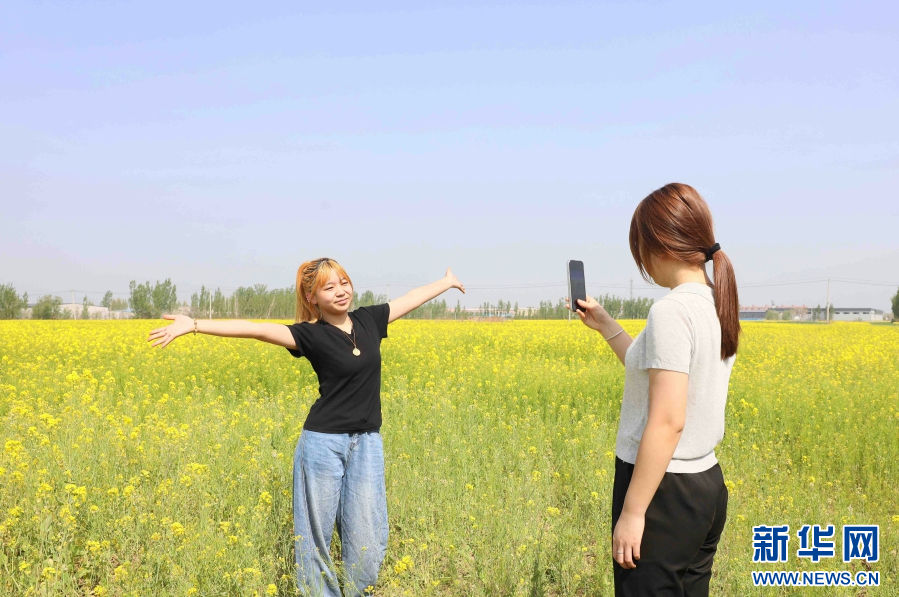游客在油菜花田里拍照打卡，尽享春光。新华网发 田优 摄