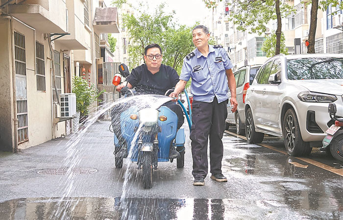 物业人员洒水洗路面，保持小区干净整洁。 本报全媒体记者 洪怀峰摄