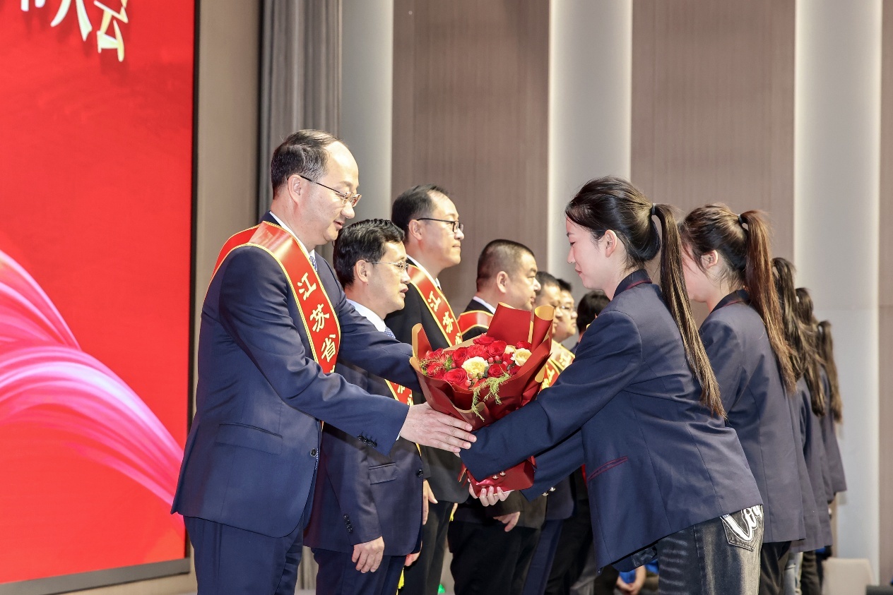 图为省靖中专校学生向靖江市新当选的江苏省劳动模范致敬献花。