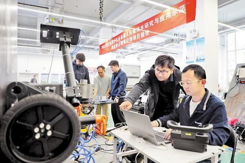 4月27日，在彼合彼方机器人（天津）有限公司一楼试验区，张小俊（右二）正指导工程师对喷漆机器人进行调试。 屠琼芳摄
