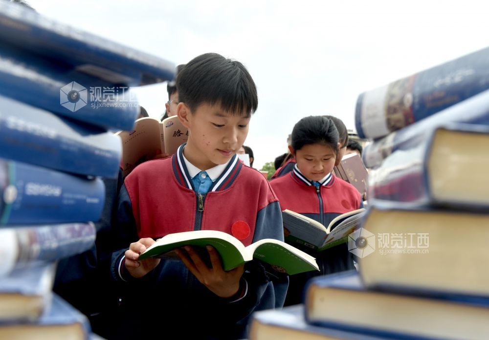 该校学生正在活动现场阅看自己喜欢的书籍。