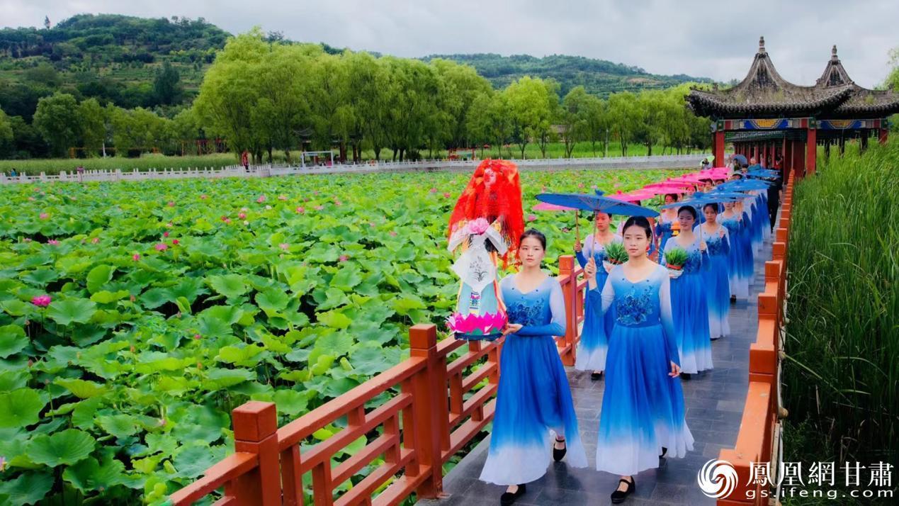 西和县乞巧节举办期间，迎巧队伍行进在晚霞湖畔。姜克尚　摄