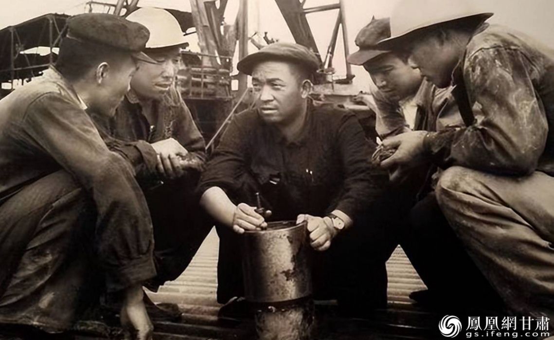 王进喜（中）与工友们研究如何提高钻井质量　资料图片