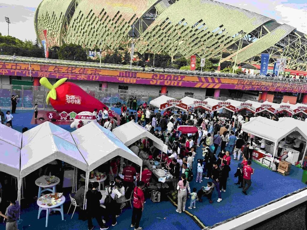 ▲在国体中心外围的“赣超集市”上，售卖江西小炒与清爽冷饮的摊位前挤满了球迷。摄影丨江西日报全媒体记者周珺
