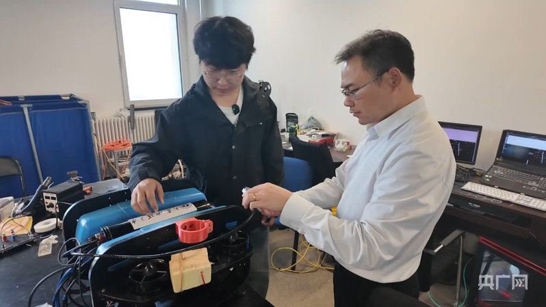 林远山给张海光讲解机械原理（央广网记者 易博闻 摄）