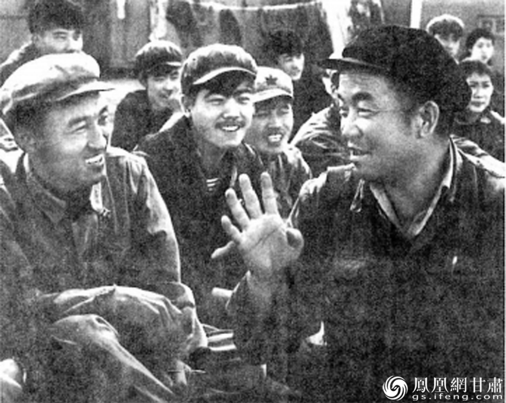 王进喜（右一）与工人们谈心　资料图片