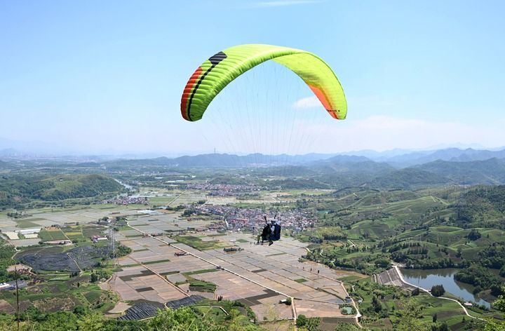 2026年5月1日,游客在浙江省金华市武义县大斗山飞行营地乘坐滑翔伞。新华社发(张建成 摄)