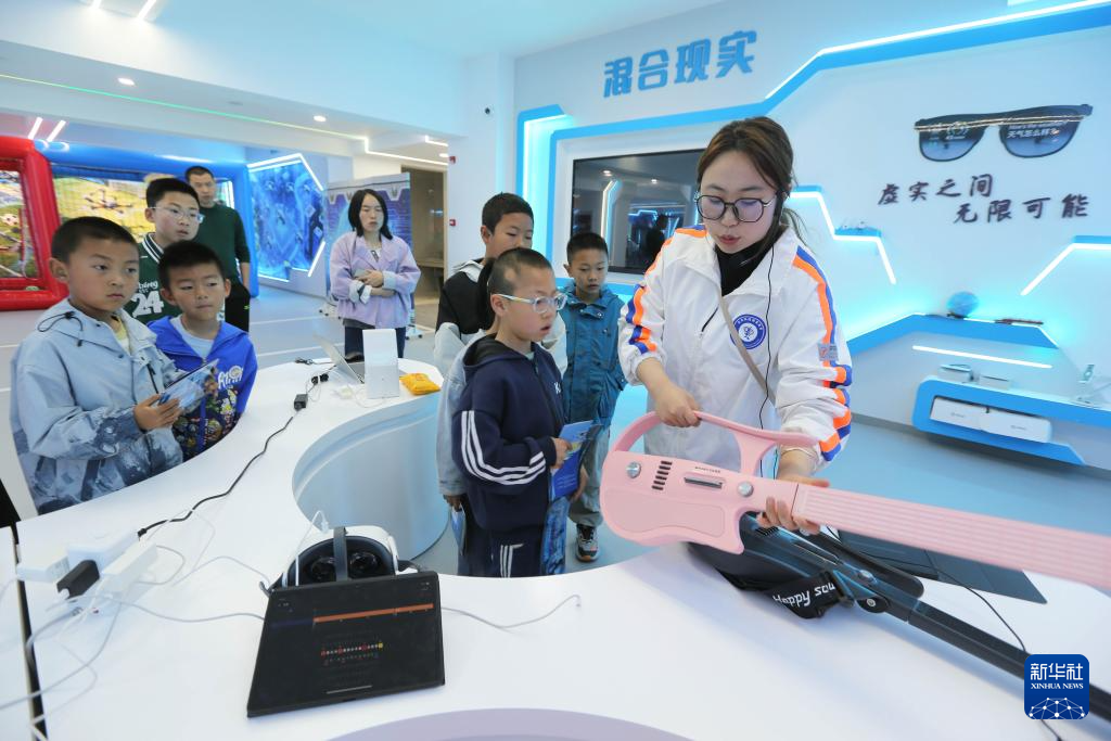 5月7日,甘肃省定西市安定区人工智能教育基地的工作人员向学生展示AI吉他。新华社发(王克贤 摄)