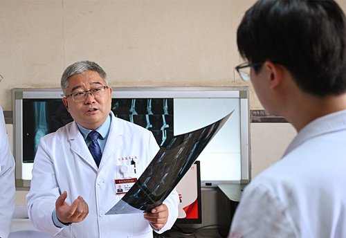 4月28日，陈伟（左）向年轻医生讲解骨折患者的手术方案。本报记者 赵永辉摄