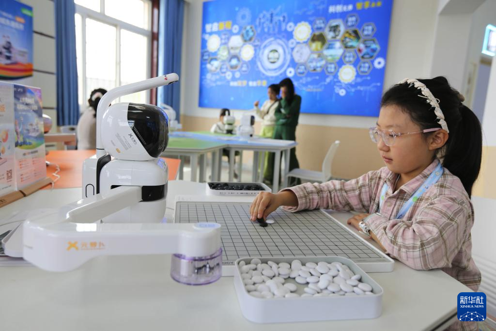5月7日,学生在甘肃省定西市安定区科技馆和智能机器人对弈。新华社发(王克贤 摄)
