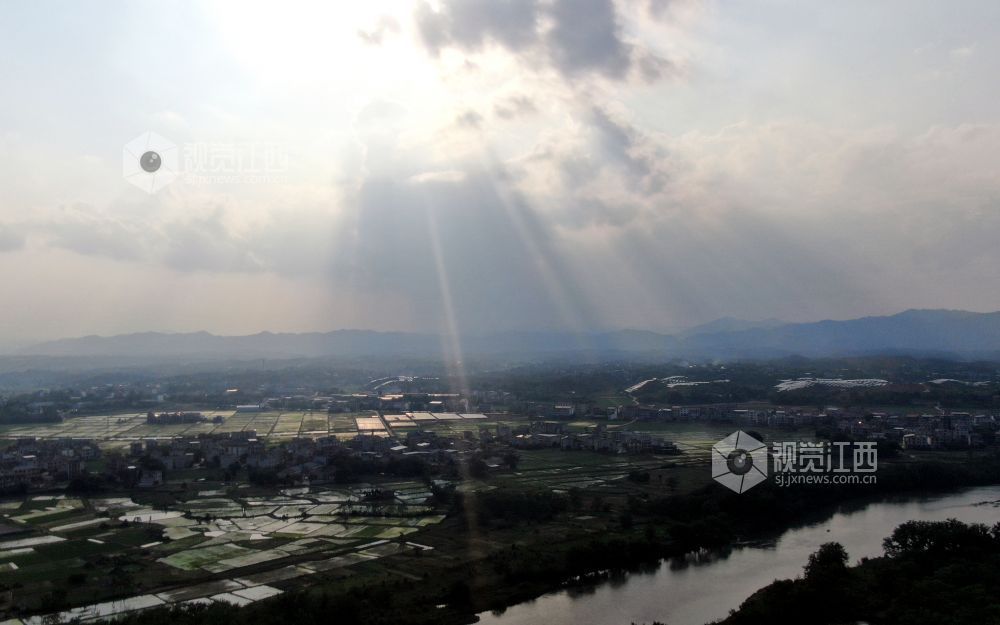 2026年5月6日，江西省遂川县泉江河畔，丁达尔光透过云层洒向大地，为河湾、稻田与错落民居镀上柔光，青山如黛，绿水含情，乡村田园风光如画，尽显生态之美与春日生机。
