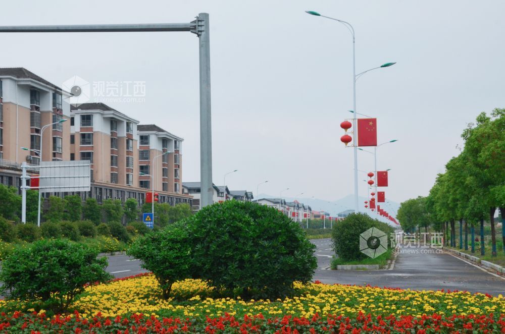 5月9日，在江西省吉安市永新县城区周边道路上，花卉景观与居民楼、路灯共同构成整洁优美的城市街景。
