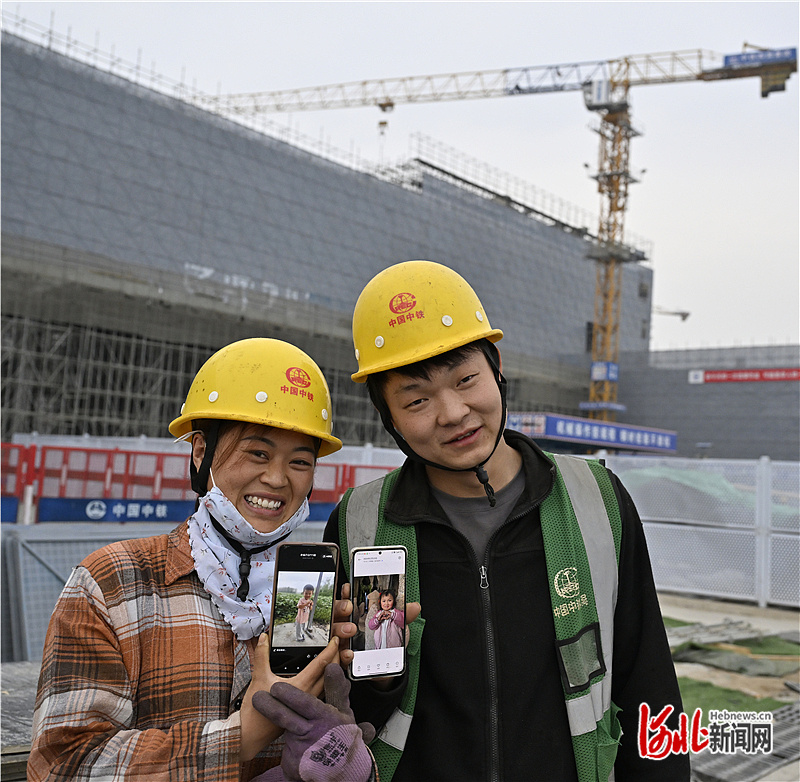4月8日，北京科技大学雄安校区建设工地，来自河南的建设者陈记（右）和夏群群夫妇展示手机里孩子的照片，在工地留下难忘的合影。
