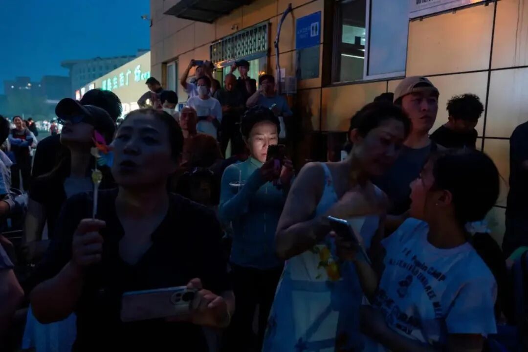 ◆5月13日晚，人们在北京首都国际机场外等候美国总统的专机抵达。（图源：美联社）