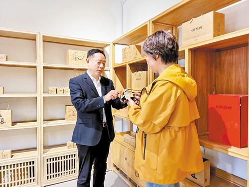 4月28日，在“相逢赵州”共富工坊，赵县冀华星果品专业合作社负责人安青川（左）向游客介绍雪梨膏产品。本报记者 郝东伟摄