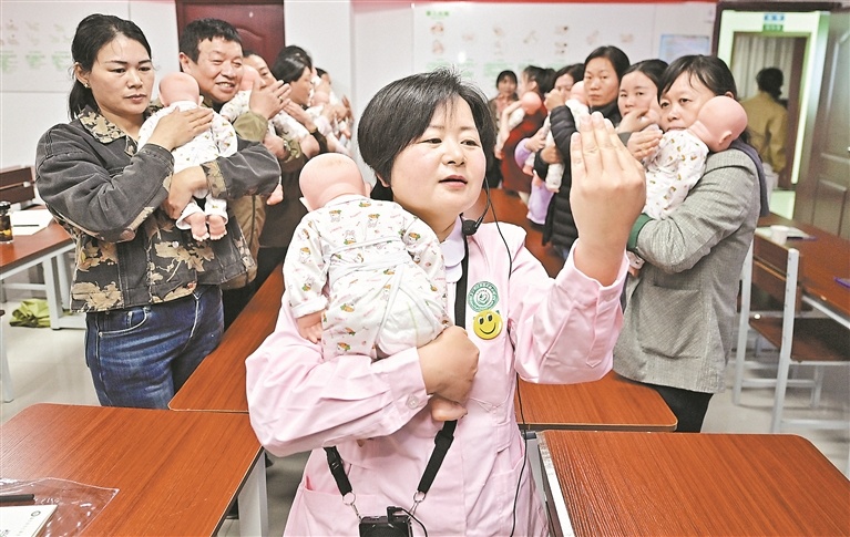4月21日，培训教室内，陈英向学员示范如何给婴儿拍嗝。