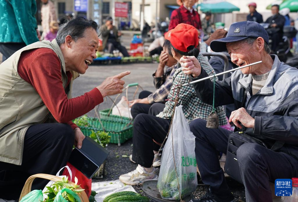 一名菜农（右一）为附近居民称量蔬菜（5月12日摄）。