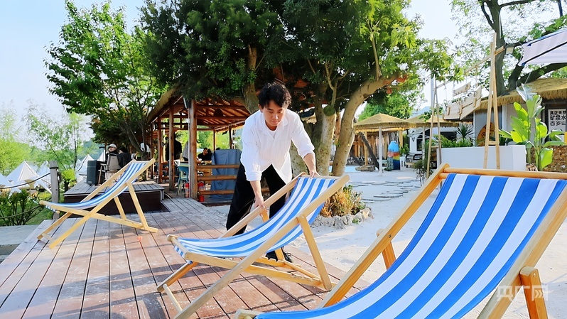 翟松在湖畔营地整理躺椅(央广网记者 任振国 摄)