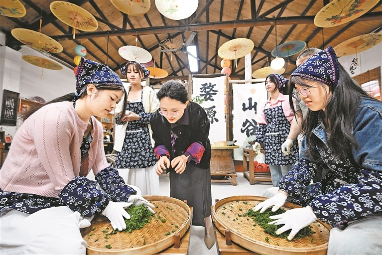 4月8日，在婺源县思口镇一家非遗体验中心，中心负责人程卫华（左三）指导游客学习体验婺源绿茶制作技艺中的揉捻环节。