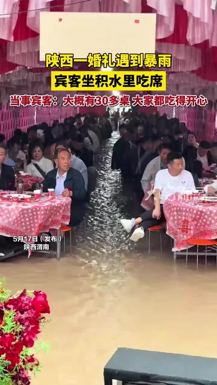 陕西一婚礼遇到暴雨 宾客坐积水里吃席 当事宾客：大概有30多桌 大家都吃得开心