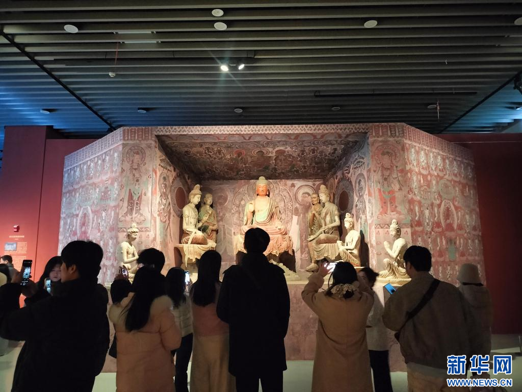 图为“釉色里的敦煌”展现场，观众在敦煌莫高窟第328窟(官方复制窟)前拍照。受访者供图
