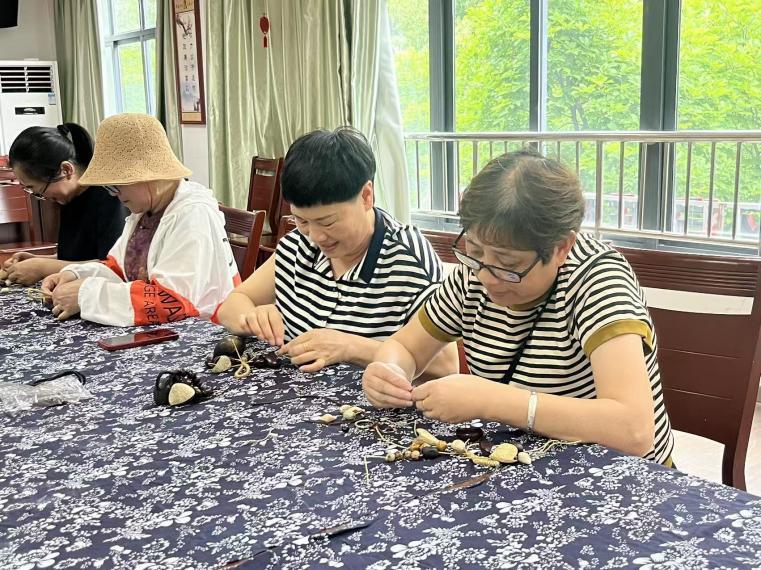 图为居民制作果壳摇铃中