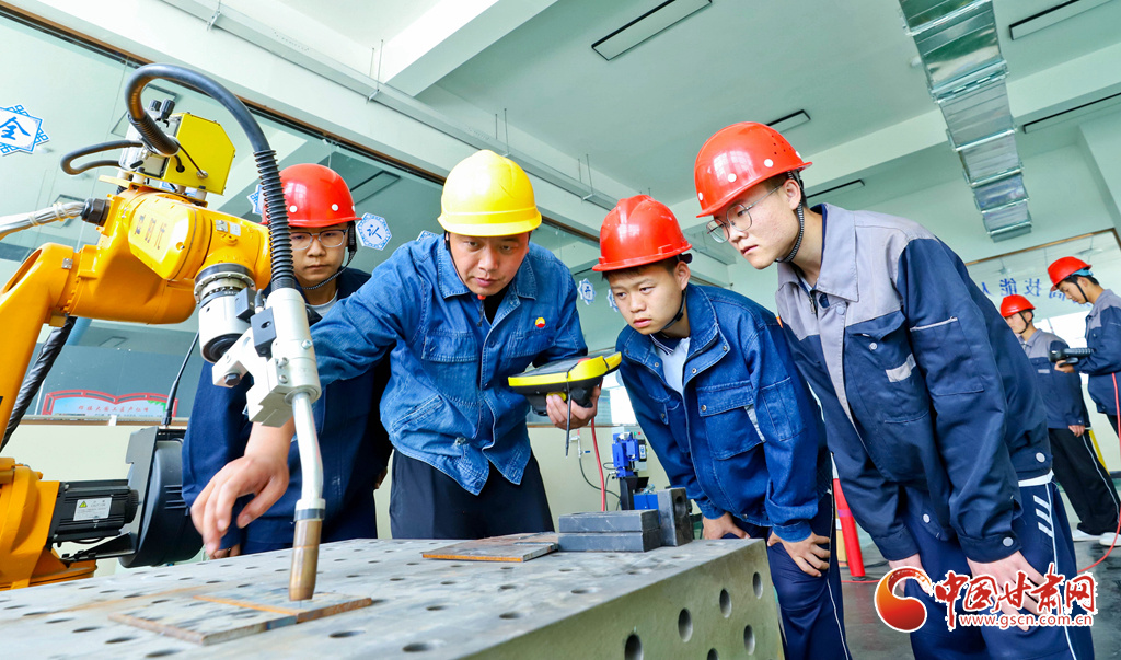 老师正在指导学生掌握机器人焊接程序要点
